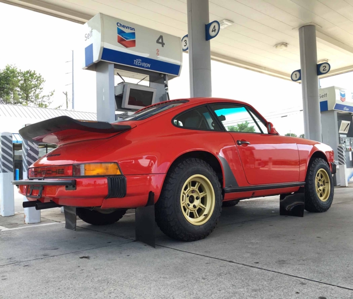 Custom Built 1986 Porsche 911 Carrera in Indian Red with Porsche Studiocheck Interior parked at a gas station