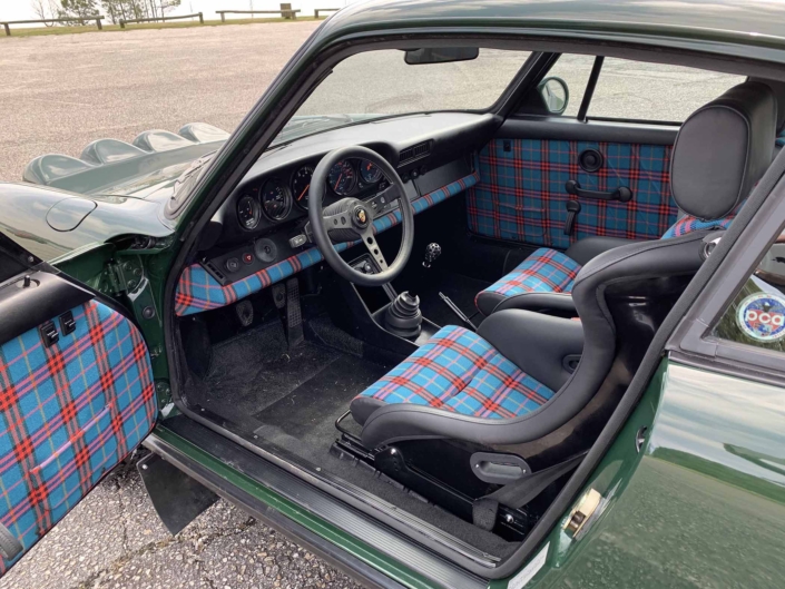 Custom built 1982 Porsche 911 SC in Irish Green with VW tartan interior parked with the door open showcasing the interior