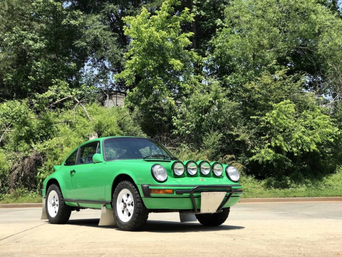 Custom Built 1981 Porsche 911 SC in Signal Green with Porsche Tartan Interior parked on the dirt with the woods in the background