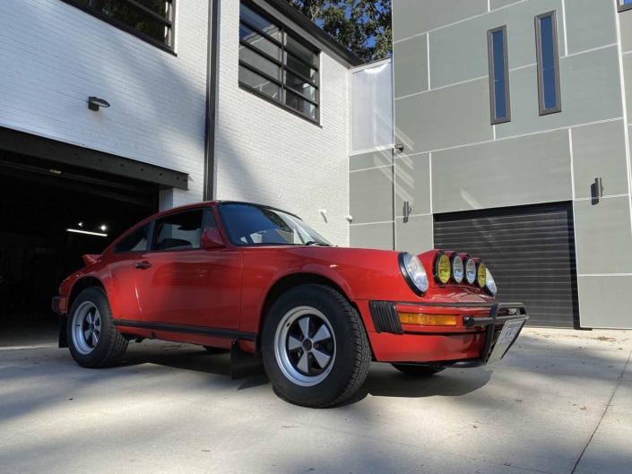 Custom Built 1987 Porsche 911 Carrera with Cherry Red exterior and VW retro interior parked in front of a modern garage
