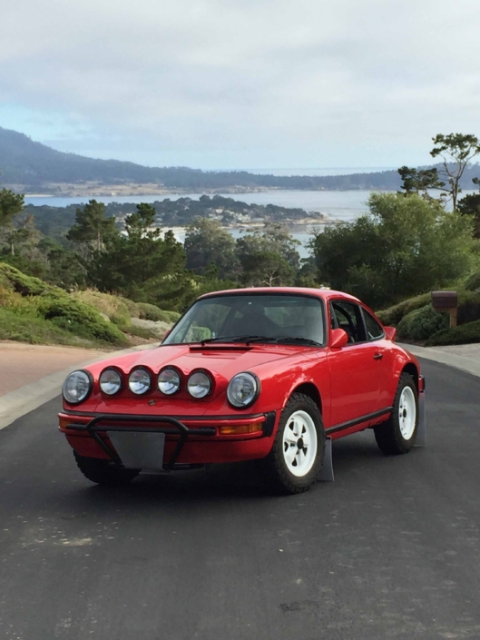 Custom Built 1981 Guards Red Porsche 911 SC parked at the top of a hill with a landscape in the background