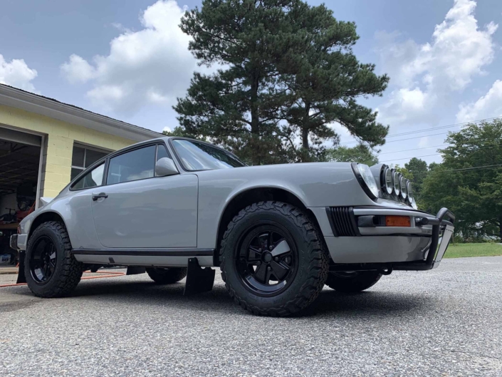 3/4 side view of a rear view of a custom 1986 Porsche 911 Carrera with Chalk exterior color and Porsche Pepita interior