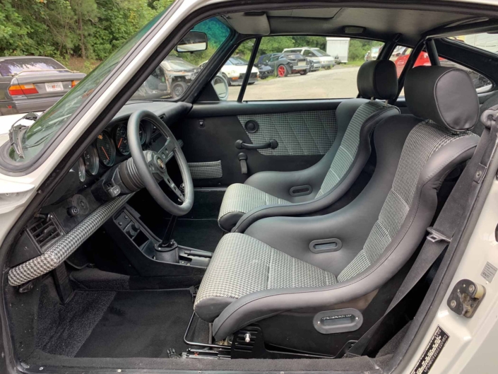 front seating in a rear view of a custom 1986 Porsche 911 Carrera with Chalk exterior color and Porsche Pepita interior