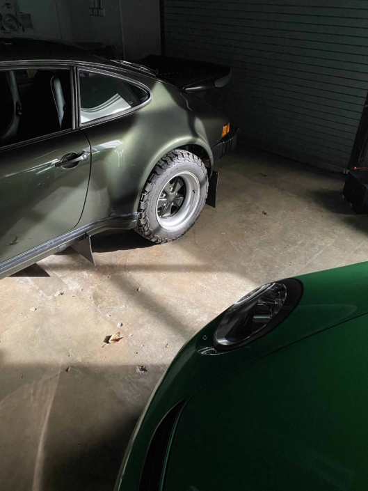 Custom Built 1986 Porsche 930 Turbo with Oak Green Metallic Exterior and Porsche tartan interior parked inside a garage