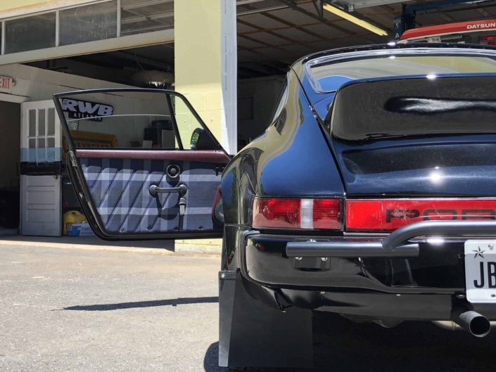 Custom Built 1986 Porsche 911 Carrera with Shwartz Exterior and Mercedes G Fabric Interior with the door open showcasing custom interior design