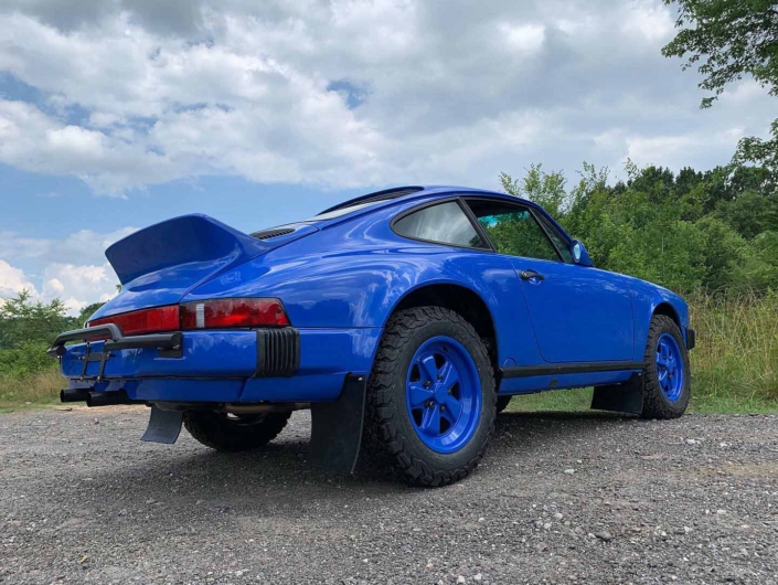 3/4 view of a Custom Built 1988 Porsche 911 Carrera in Acid Blue with Dog fabric interior with the window down