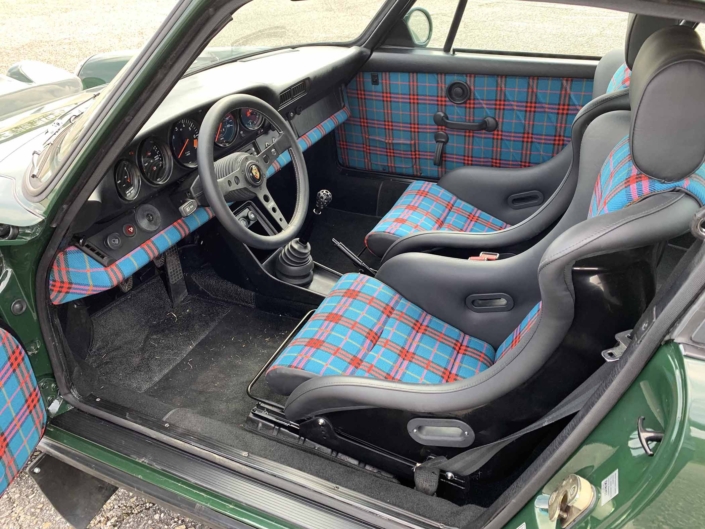 Custom built 1982 Porsche 911 SC in Irish Green with VW tartan interior parked with the door open showcasing the interior