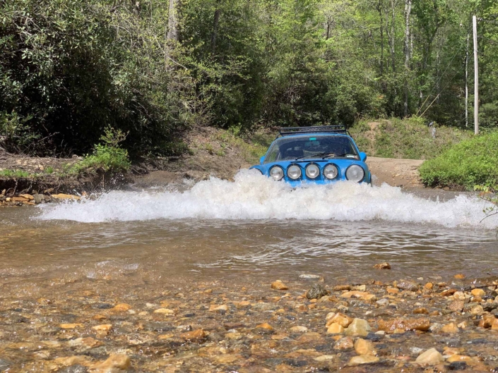 3/4 view of a Custom Built 1980 Porsche 911 SC in Riviera Blue driving through water