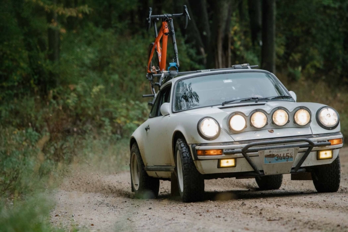 Custom Built Carrera White 1989 911 Carrera with Porsche Tartan Interior driving in the forest