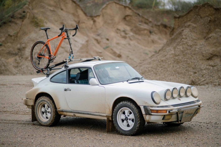 side view of Custom Built Carrera White 1989 911 Carrera with Porsche Tartan Interior with a bike on the back