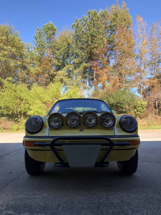 front view of a Custom Built 1984 Porsche 911 Carrera Euro with Hellgelb Exterior and Mercedes Tartan Interior parked in the shade