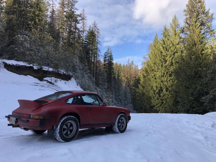 Custom Built 1987 Porsche 911 Carrera with Cherry Red exterior and VW retro interior driving through the snow