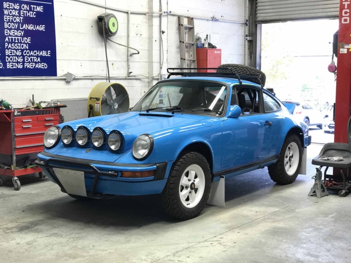 Custom Built 1980 Porsche 911 SC in Riviera Blue with blue and brown basket weave interior parked in a mechanic shop