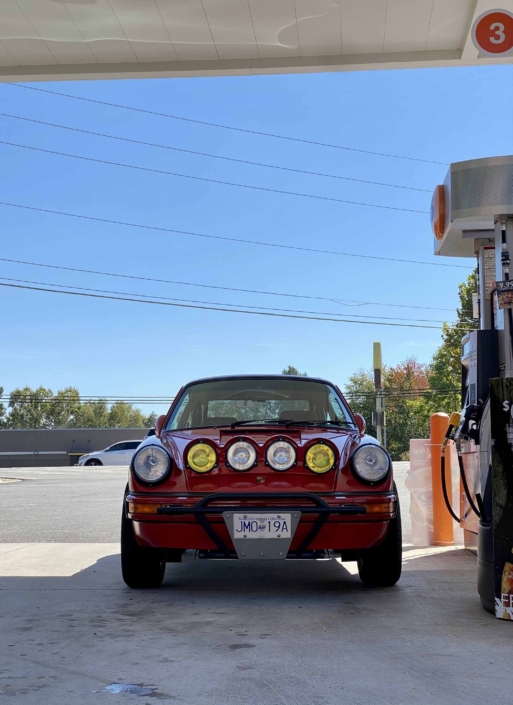 Custom Built 1987 Porsche 911 Carrera with Cherry Red exterior and VW retro interior parked at a gas station