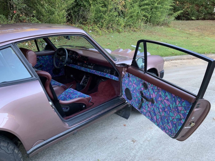 Custom Built 1987 Porsche 911 Carrera in Cassis Red with European bus fabric interior parked with the door open