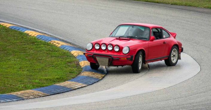 Custom Built 1981 Guards Red Porsche 911 SC making a turn on a race track