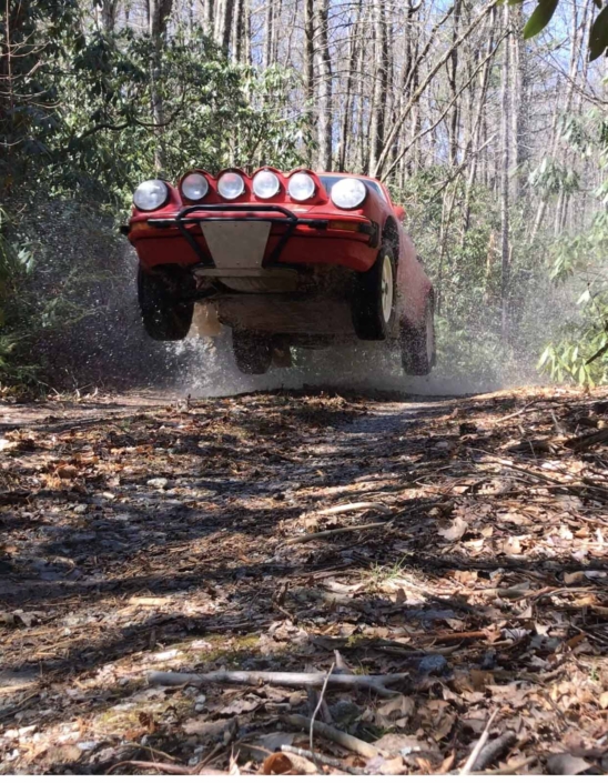 Custom Built 1981 Guards Red Porsche 911 SC mid air in the forrest
