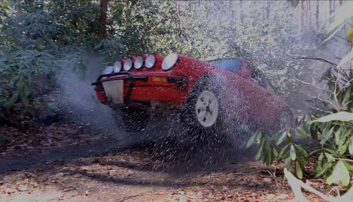 Custom Built 1981 Guards Red Porsche 911 SC mid air in the forrest