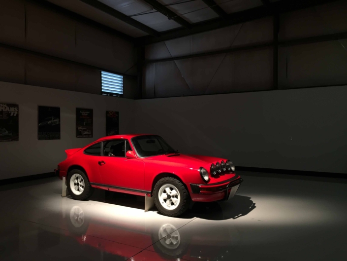 Custom Built 1981 Guards Red Porsche 911 SC parked in a dramaticly lit garage