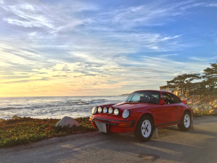 Custom Built 1981 Guards Red Porsche 911 SC on a dirt road in front of the sunset