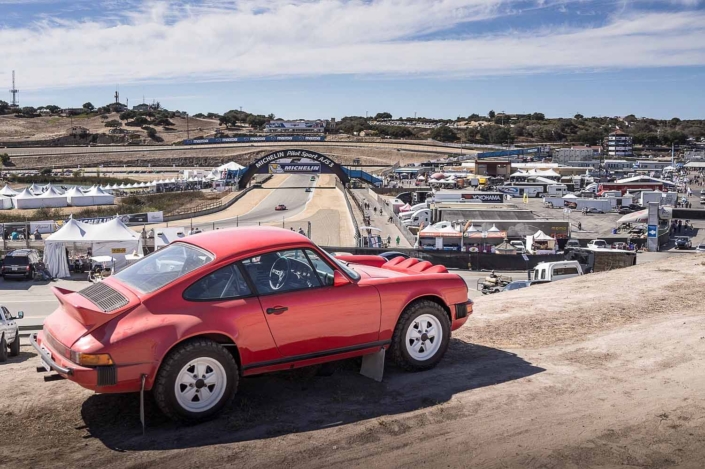 side view of a Custom Built 1981 Guards Red Porsche 911 SC driving down the road